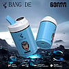 Promotional image of Bang De vaping device featuring a cartoon monkey with aviator goggles, display panel, and highlighted features including three flavors, dual coil, intelligent power indicator, and digital oil indicator, set against a rugged outdoor background.