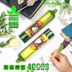 Une image de produit avec deux appareils de vape King Bang King avec un design de gorille de dessins animés, étiqueté «Strawberry Kiwi», fixé parmi des articles décoratifs comme des livres et des fleurs, avec des caractéristiques de produit comme «40, 000 bouffées» et «Type-C» ci-dessous.