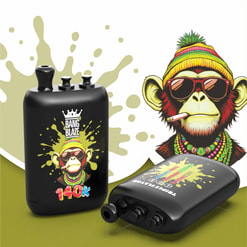 Black Vape Device With A Colorful Monkey Graphic, Shown Upright And Lying Down On A White And Olive Background