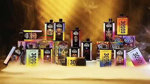 A Display Of Colorful Vaping Product Packaging, Including Disposable Vape Devices And Boxes With Vibrant Designs And Branding In A Smoky, Golden-Lit Setting.